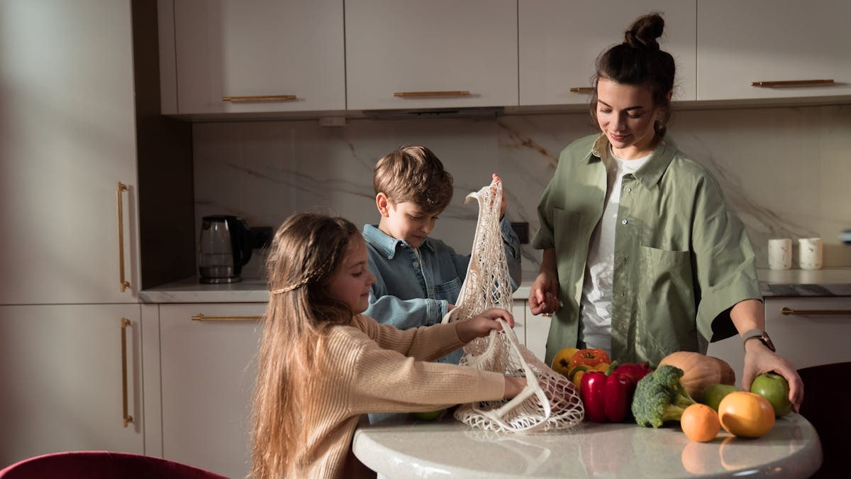 A happy family of three enjoying quality time unpacking vegetables in a modern kitchen.